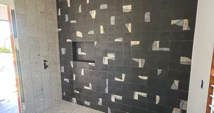 Ongoing remodeling project of a bathroom, specifically in the shower area where the backsplash needs to be replaced.