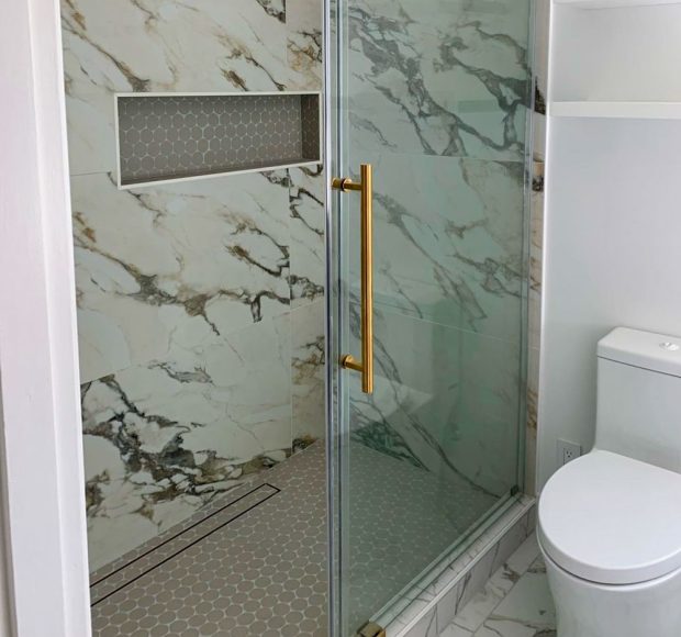 Remodeled bathroom with tile installed as floor, shower backsplash, and shower niche